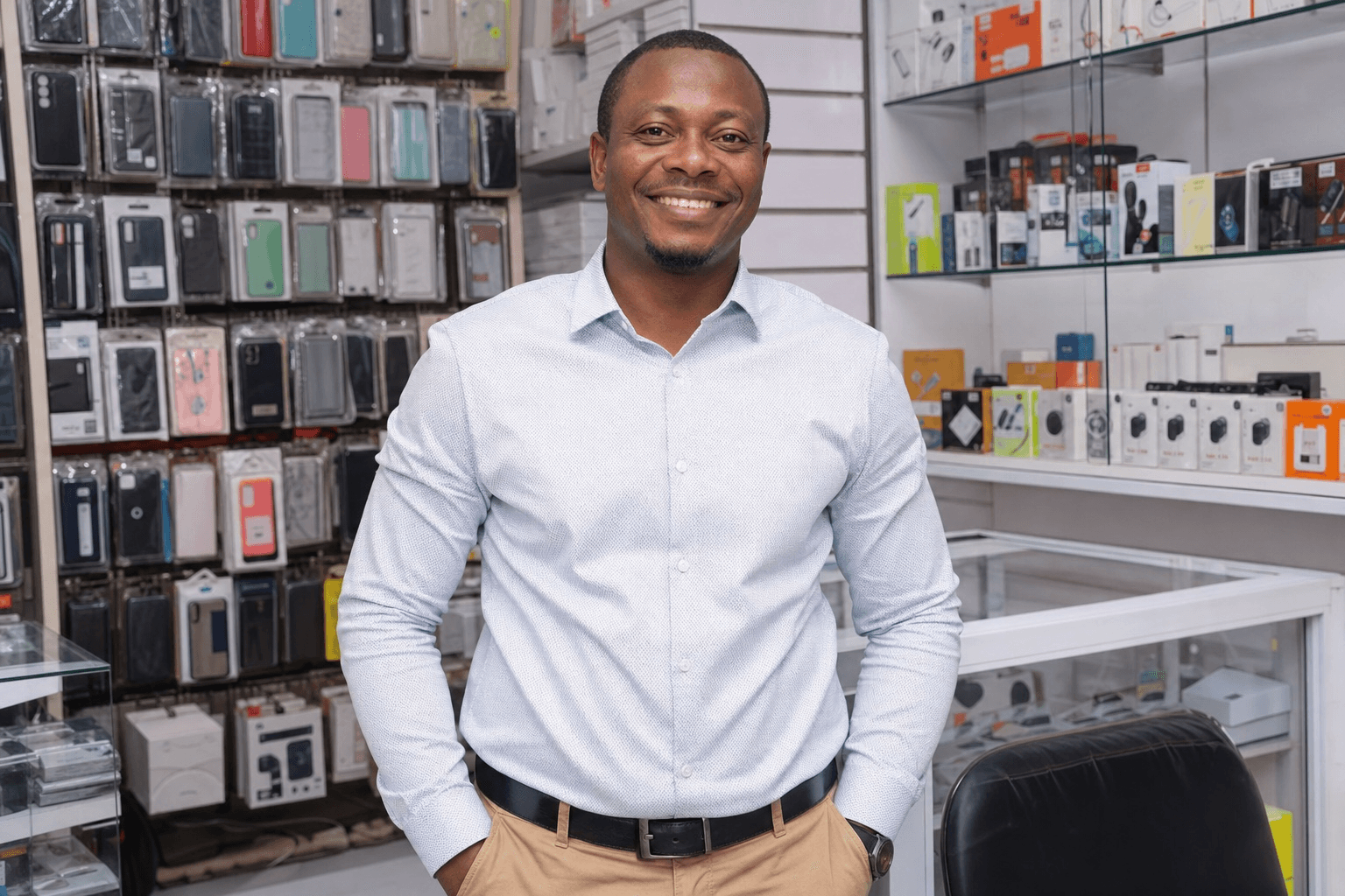 Tunde smiling in his phone accessories shop in Port Harcourt